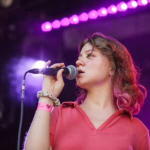 Junge Frau singt in ihr Mikrofon.